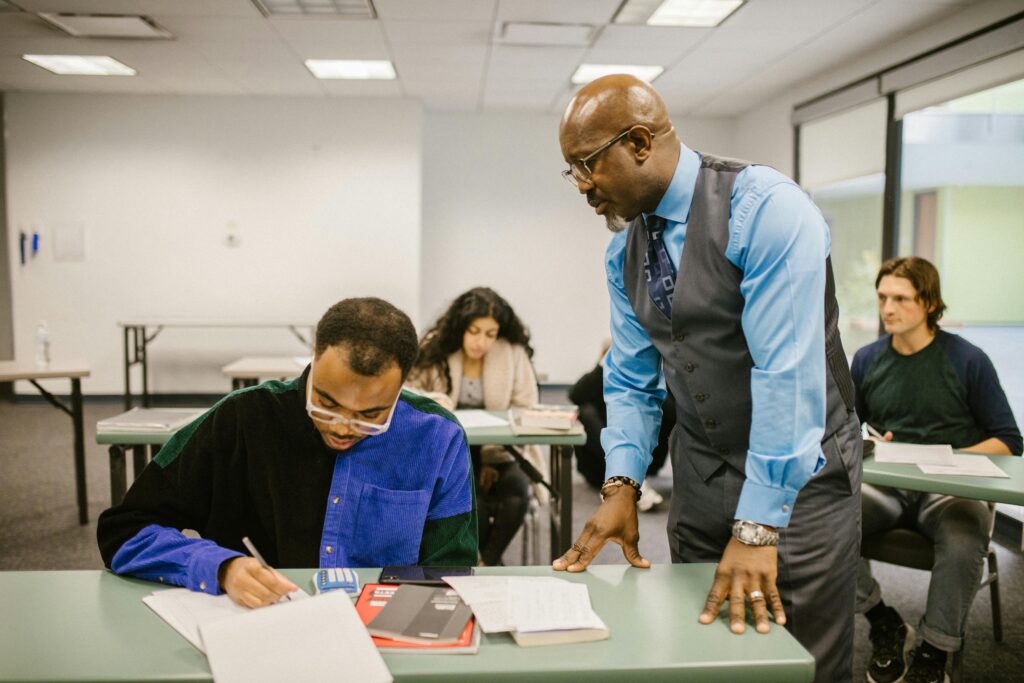 Educator supervising students during a test in a college classroom.