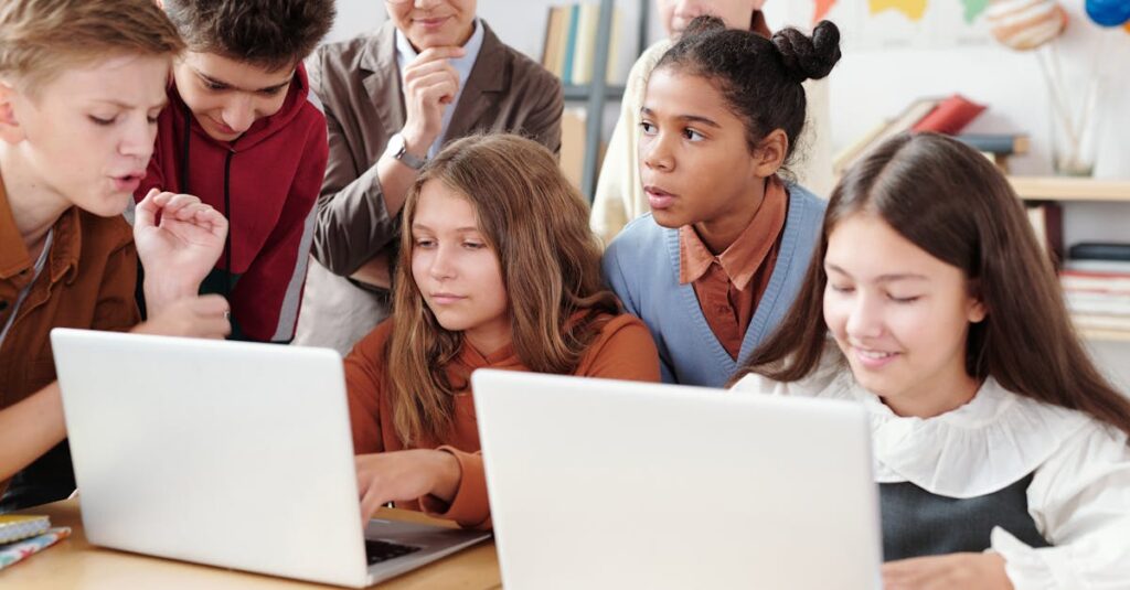 Teenage students actively collaborate on laptops in an educational environment with guidance from a teacher.