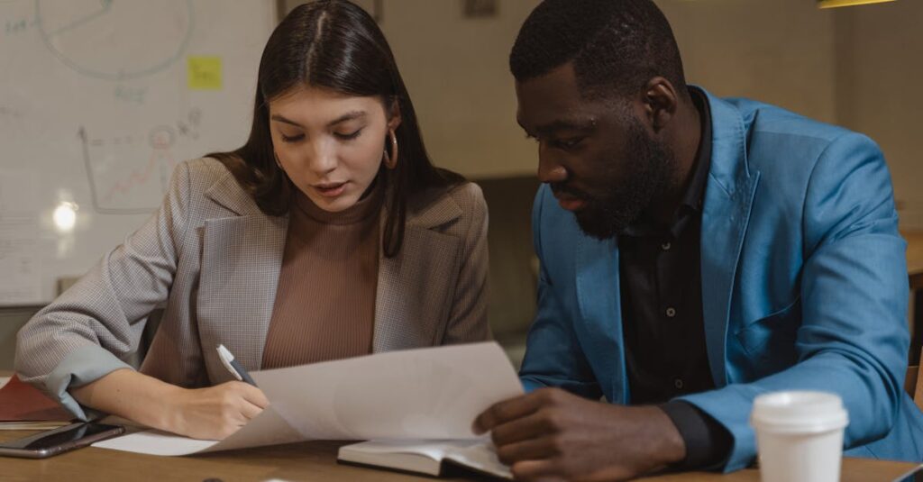 Two colleagues collaborating over documents at an office desk.
